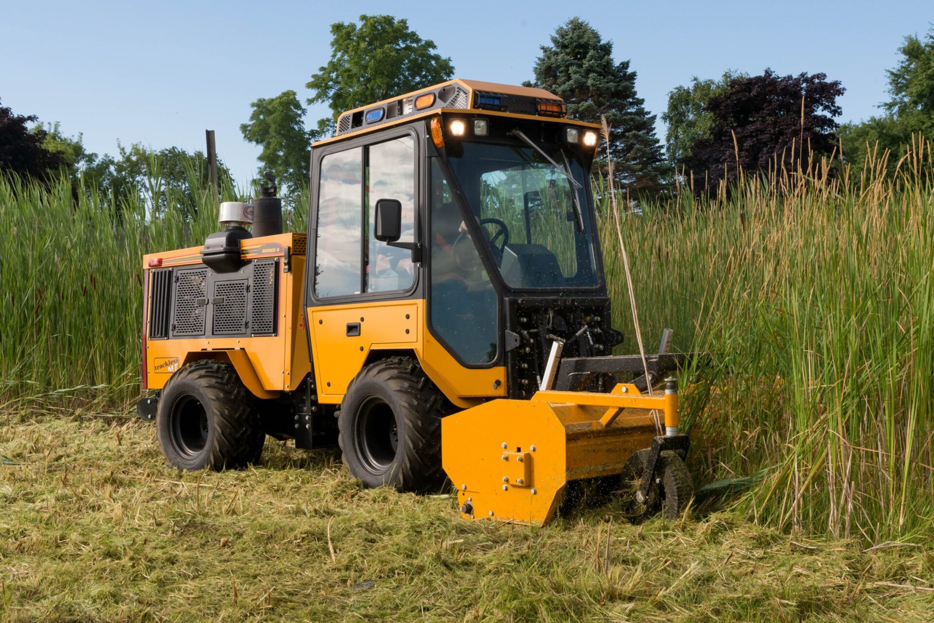 trackless vehicles mt6 tractor with front flail mower mowing very tall grass