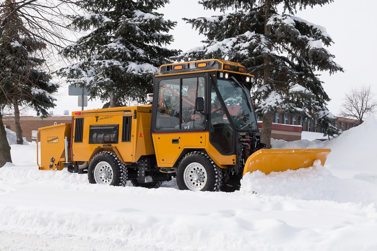 trackless vehicles double trip plow attachment on sidewalk tractor in snow side view