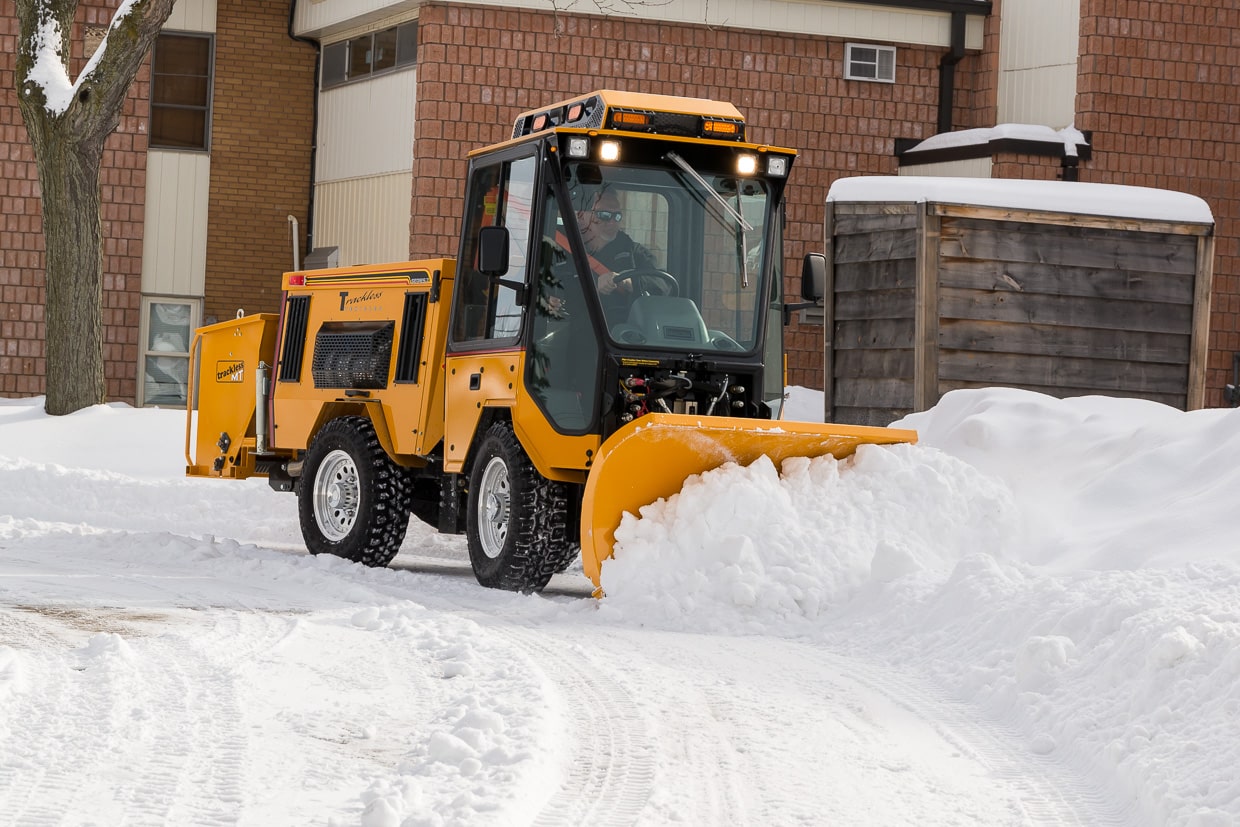 trackless vehicles double trip plow attachment on sidewalk tractor in snow side view