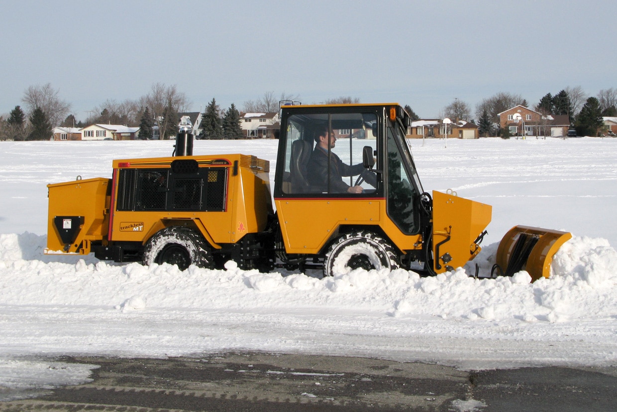 trackless vehicles front-mount spreader and plow attachment on sidewalk tractor in snow side view