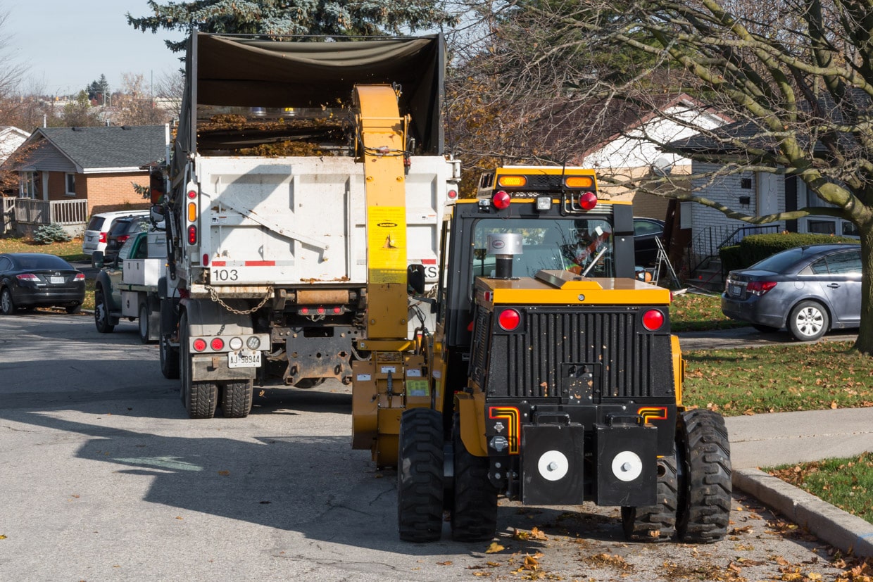 trackless vehicles leaf loader attachment on sidewalk municipal tractor loading leaves rear view