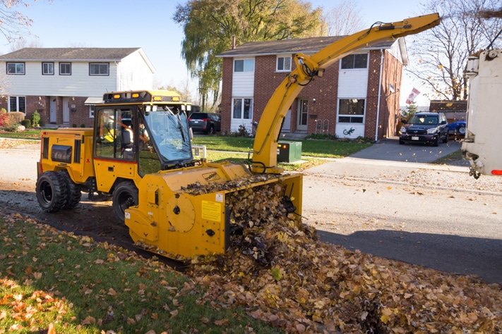 trackless vehicles leaf loader attachment on sidewalk municipal tractor loading leaves side view