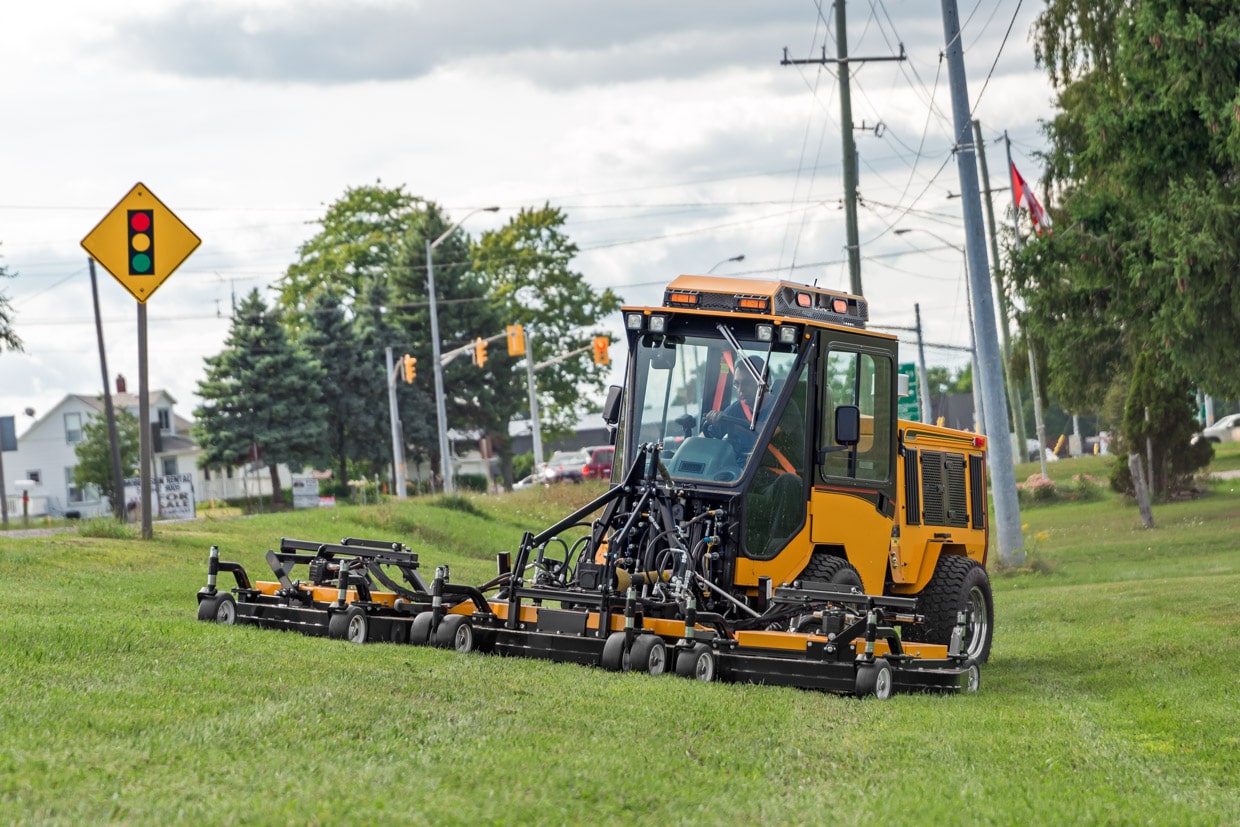 trackless vehicles progressive turf 14' mower attachment on sidewalk municipal tractor mowing grass front view