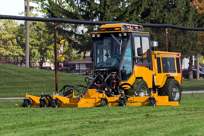 trackless vehicles rotary finishing mower 14' attachment on sidewalk municipal tractor mowing grass front side view