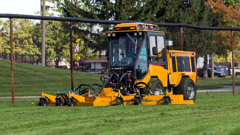 trackless vehicles rotary finishing mower 14' attachment on sidewalk municipal tractor mowing grass front side view