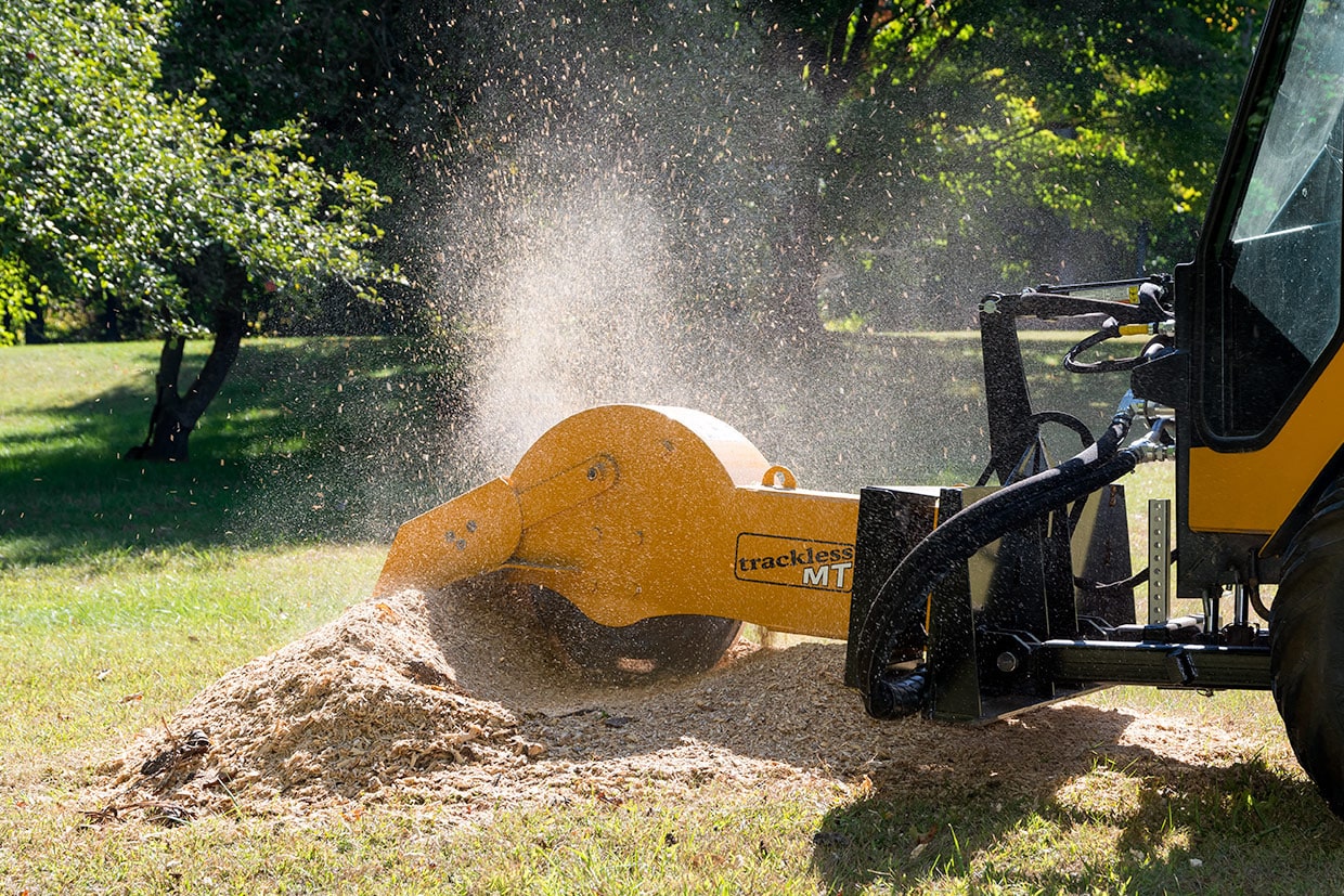 trackless vehicles stump grinder attachment on sidewalk municipal tractor grinding stump side view close-up