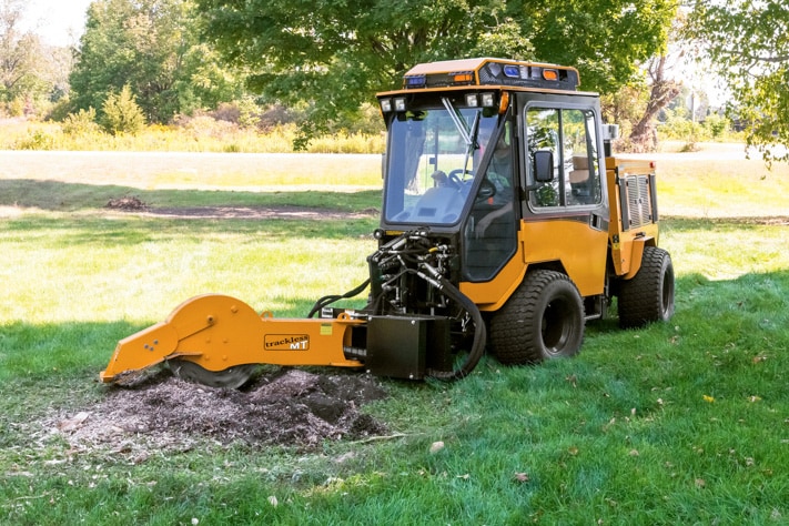 trackless vehicles stump grinder attachment on sidewalk municipal tractor grinding stump front view