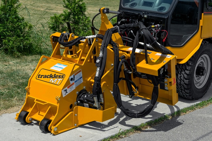 trackless vehicles cold planer attachment on sidewalk tractor working on sidewalk side view close-up